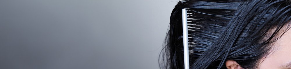 Duże zbliżenie na grzebień rozczesujący mokre ciemne włosy